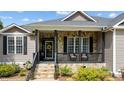 Cozy front porch featuring stone accents, a black railing, and a welcoming wreath on the front door at 503 Fish Pond Ct, Rolesville, NC 27571