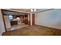 Open-concept living room view into kitchen with brown carpet and wood trim at 530 Broad Rd, Roxboro, NC 27573