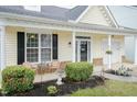 Inviting front porch featuring black shutters, flower pots, and lovely landscaping at 59 Tuscarora Ln, Clayton, NC 27520