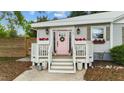 Inviting front porch adorned with flower boxes and potted plants flanking a charming pink front door with glass details at 703 E Horne St, Clayton, NC 27520