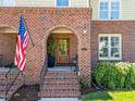 Inviting brick entryway with arched doorway, featuring a charming wooden door and a welcoming American flag at 714 Mordecai Towne Pl, Raleigh, NC 27604