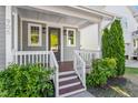 Inviting covered front porch with wood stairs and white railings, complemented by lush landscaping at 905 Moye Dr, Raleigh, NC 27606