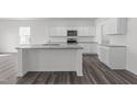 Spacious kitchen showcasing white cabinets, a granite island, modern appliances, and stylish dark wood flooring at 103 Gladstone Loop, Clayton, NC 27520