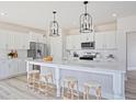 Stylish white kitchen features a large island with seating, stainless steel appliances, and modern lighting at 1107 Shovelhead Dr # Homesite 39, Durham, NC 27703