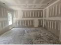 Unfinished living room with gray drywall, concrete floors and a large window at 143 Mildred Place, Broadway, NC 27505