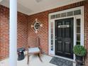 Inviting front porch with brick accents, decorative door, and a cozy rocking chair at 2067 White Pond Ct, Apex, NC 27523