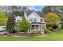 Attractive home with a covered front porch, surrounded by mature trees and vibrant landscaping at 402 Green Turret Dr, Rolesville, NC 27571