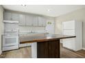Eat-in kitchen with gray cabinets, white appliances, a center island, and wood-look vinyl flooring at 500 John St St, Clayton, NC 27520