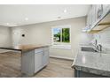 Open kitchen view with gray cabinets, granite counters, island with wood top, and stainless steel sink and faucet at 500 John St St, Clayton, NC 27520