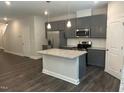 Open-concept kitchen design with a gray kitchen island, stainless steel appliances, and modern lighting fixtures at 540 Eversden Dr, Zebulon, NC 27597