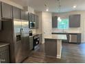 Modern kitchen featuring stainless steel appliances, gray cabinets, granite countertops, and a central island at 540 Eversden Dr, Zebulon, NC 27597