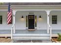 Close up of the front door and covered front porch with patriotic American flag at 5541 Old Still Rd, Wake Forest, NC 27587