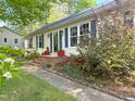 Charming single-story home with a brick entrance, vibrant flowerbeds, and manicured lawn at 700 Sawmill Rd, Raleigh, NC 27615