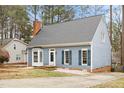 Inviting one-story home featuring a brick chimney, blue siding, shuttered windows, and a welcoming front yard at 7112 Benhart Dr, Raleigh, NC 27613