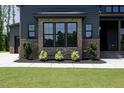 Up close view of a well-manicured gray home with brick base, mature shrubs, and walkway at 8620 Dukes Lake Rd, Zebulon, NC 27597