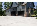 Three-car garage and side door entry to home, featuring black garage doors and concrete parking at 8620 Dukes Lake Rd, Zebulon, NC 27597