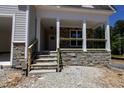 Inviting covered front porch with stone accents, wooden railing, and classic columns at 90 Purslane Dr, Franklinton, NC 27525