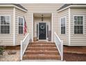 Inviting front entrance with brick steps, white railings, and a decorative wreath on a black front door at 106 Teak Cir, Garner, NC 27529