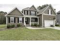 Charming two-story home featuring a welcoming front porch, attached garage, and lush green lawn at 1108 Agio Ct, Zebulon, NC 27597