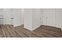 Hallway featuring wood-look flooring, white walls, and multiple doorways, creating a bright and open space at 133 Gladstone Loop, Clayton, NC 27520
