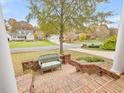Inviting front porch features a vintage green wicker bench, a brick-paved walkway, and a lush green lawn at 206 Arbor Dr, Elon, NC 27244
