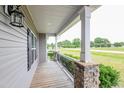 Inviting covered front porch featuring sturdy stone pillars, a wooden deck, and great neighborhood views at 24 Cider Ct, Benson, NC 27504