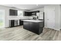 Well lit kitchen featuring dark cabinetry, stainless steel appliances, and an island with a white countertop at 66 Furley St, Sanford, NC 27330