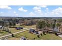 Aerial view of stately home surrounded by grassy yard with bordering woods creating a serene and private atmosphere at 80 Greta Ln, Henderson, NC 27537