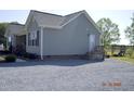 Exterior view of home featuring gravel driveway, tidy landscaping, and access to back entrance at 860 Bear Rd, Benson, NC 27504