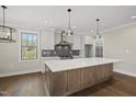 Modern kitchen with white cabinets, stainless steel appliances, a large island and hardwood floors at 10119 Second Star Ct, Raleigh, NC 27613