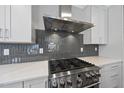 Close-up of the gas range, quartz countertop and gray subway tile backsplash in the modern kitchen at 10119 Second Star Ct, Raleigh, NC 27613