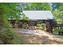 Charming wood home featuring a metal roof, lush landscaping, and a brick walkway to the front door at 1355 Bowling Road, Fuquay Varina, NC 27526