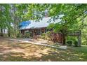 Charming wood home featuring a metal roof, lush landscaping, and a bridge connecting to the main structure at 1355 Bowling Road, Fuquay Varina, NC 27526