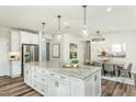 Open kitchen with a large island, stainless steel appliances, and a view to the dining area at 1809 Angelonia Way, Fuquay Varina, NC 27526