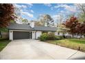 A modern home featuring a driveway leading to an attached garage with a dark gray door and a well-maintained lawn at 3016 Sylvania Dr, Raleigh, NC 27607