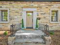 Close-up of the home's front entrance featuring stone steps, black railings, potted plants, and a natural wood door at 511 Circle Dr, Burlington, NC 27215