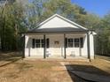 Eye-catching home with a contrasting color scheme with a welcoming porch and crisp white siding, nestled in a wooded area at 5875 Green Pine Rd, Cedar Grove, NC 27231