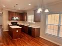Kitchen with cherry cabinets, center island, black appliances, and wood flooring at 104 Mainline Sta, Morrisville, NC 27560