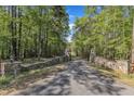 Long driveway leading to the house, lined by a stone wall and towering green trees at 11209 Sedgefield Dr, Raleigh, NC 27613