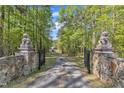Gated driveway entrance flanked by stone pillars and lion statues, leading to the house at 11209 Sedgefield Dr, Raleigh, NC 27613
