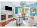 Cozy living room with a fireplace, large windows, hardwood floors, and comfortable seating, perfect for relaxation at 117 Buena Vista Dr, Cary, NC 27513