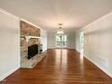 Bright living room with brick fireplace, hardwood floors, and modern light fixture at 145 Brannigan Pl, Cary, NC 27511