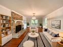 Bright, virtually staged living room with brick fireplace, modern light fixture, and french doors at 145 Brannigan Pl, Cary, NC 27511
