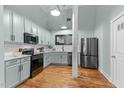 Stylish kitchen with stainless steel appliances, painted cabinets, and hardwood floors at 1535 Caraleigh Mills Ct # 104, Raleigh, NC 27603