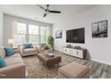 Bright living room featuring a ceiling fan, large windows, and cozy seating at 1817 Shady Oaks Dr, Wendell, NC 27591