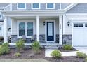 Inviting front porch with seating and stone accents that leads to a stylish front door at 1950 Menet St, Apex, NC 27502