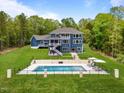 The backyard features a gorgeous in-ground pool with water features, lounge chairs, and manicured lawn at 255 Seven Island Rd, Pittsboro, NC 27312