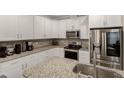 Well-lit kitchen featuring white cabinets, granite countertops, and stainless steel appliances at 375 Alcock Ln, Youngsville, NC 27596