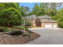 Expansive brick home with a circular driveway, lush landscaping, and serene pond at 417 Swans Mill Xing, Raleigh, NC 27614