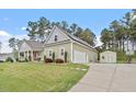 View of home with detached garage, long driveway, well manicured lawn, and a storage shed at 115 Mill Run Ln, Sanford, NC 27330